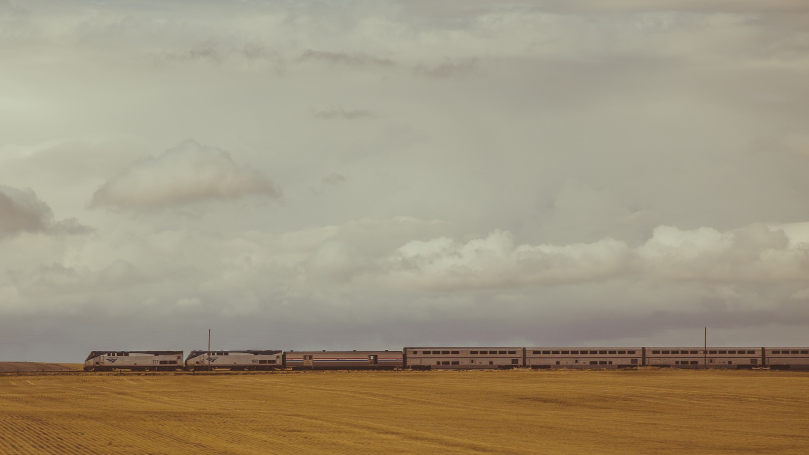 Amtrak Empire Builder passenger train crossing open farmland near Inverness, Montana, along the BNSF-hosted route used west of Minot.