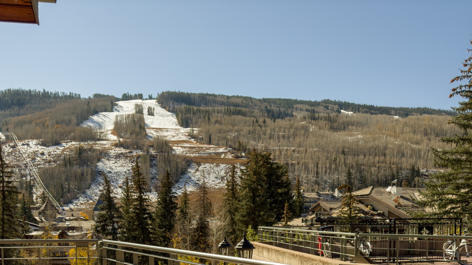 Vail Village rooftops with ski slopes carrying early-season snow under a clear sky in late October