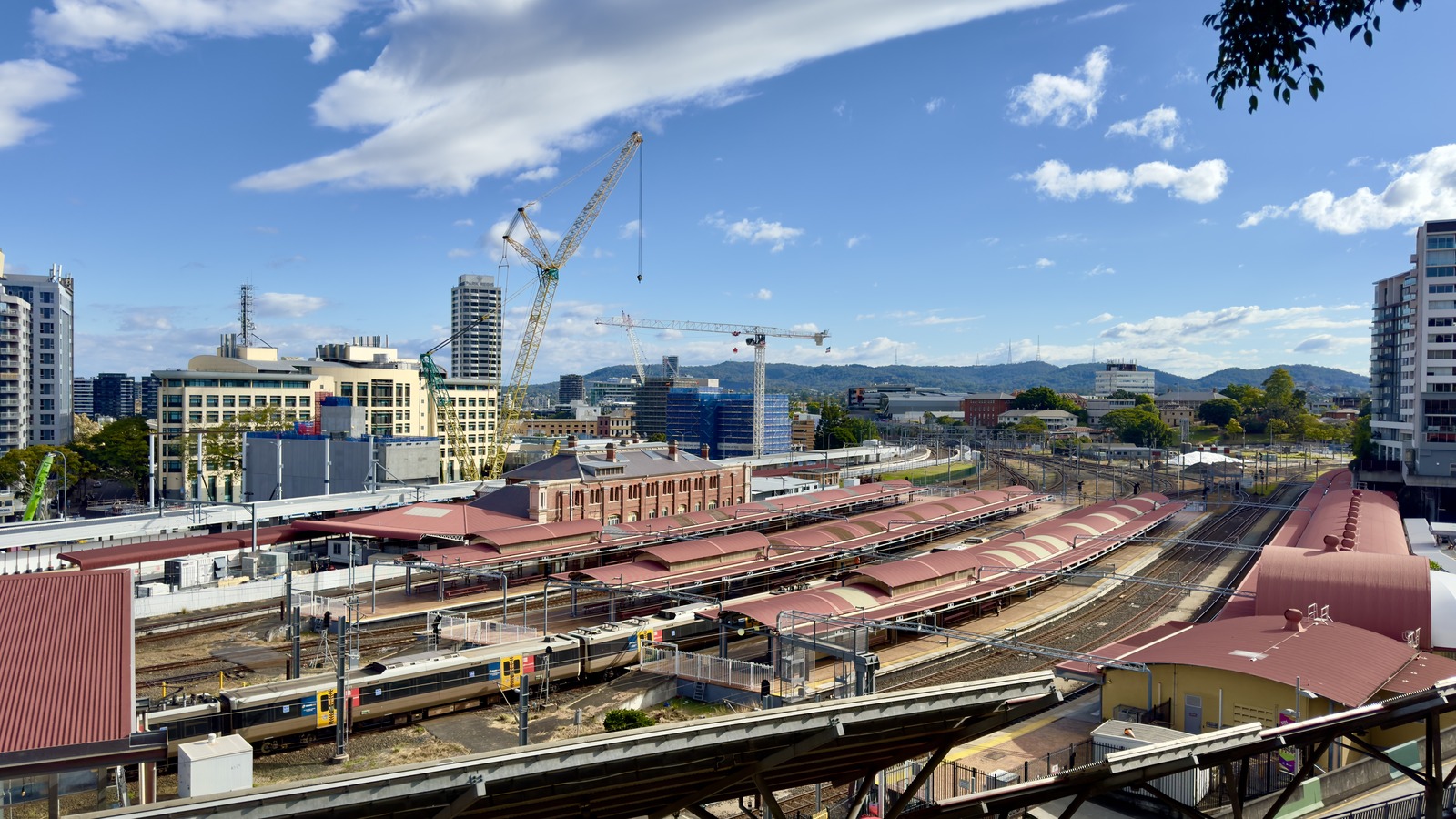 Queensland Rail train standing at Roma Street station platforms in Brisbane under a clear sky