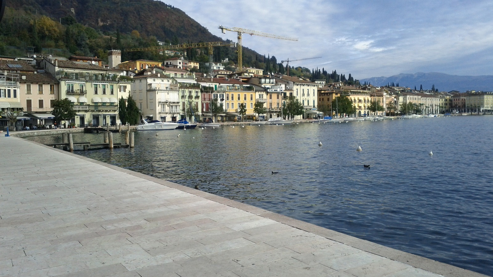 The tiled lakeside promenade and colorful waterfront buildings of Salo on Lake Garda, with boats along the quay.