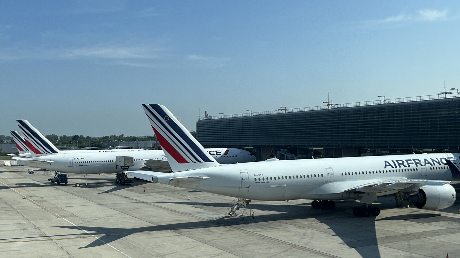 Air France jets parked at gates at Paris Charles de Gaulle Airport under a clear blue sky.