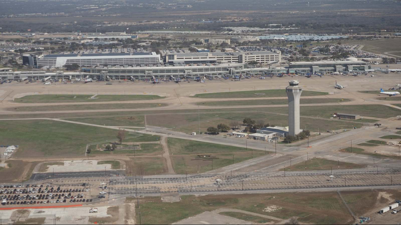 Aerial view of Austin-Bergstrom International Airport showing the terminal, parking garages, control tower and taxiways.
