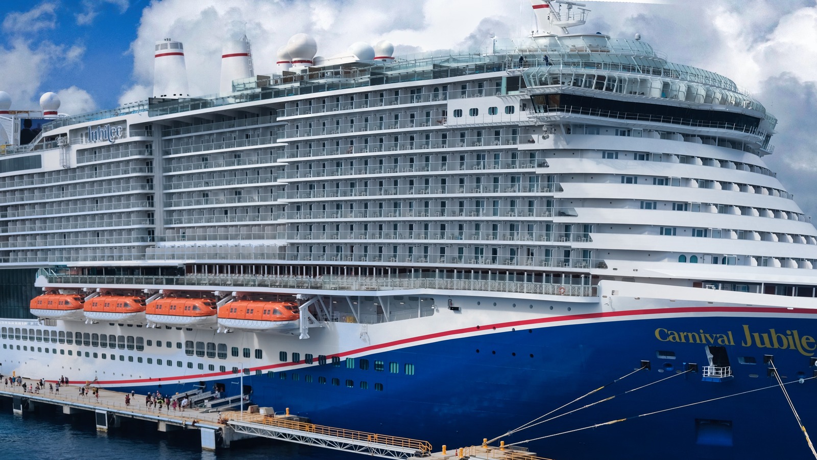 Carnival Jubilee, the blue-hulled Excel-class cruise ship, docked at Cozumel, Mexico, with the ship name visible on the bow