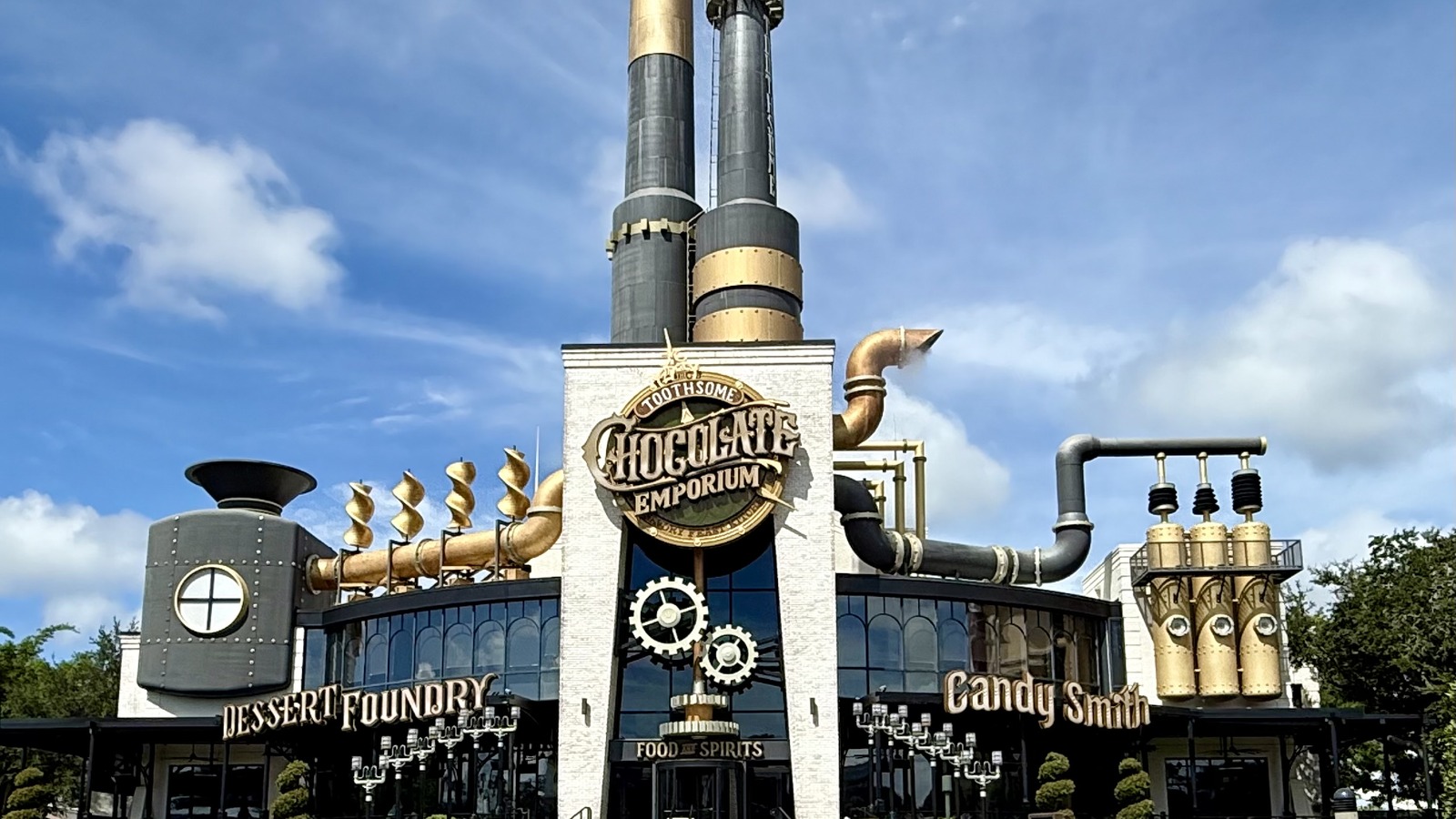 Daytime exterior of Toothsome Chocolate Emporium at Universal CityWalk in Orlando, with the steampunk smokestacks and Chocolate Emporium sign