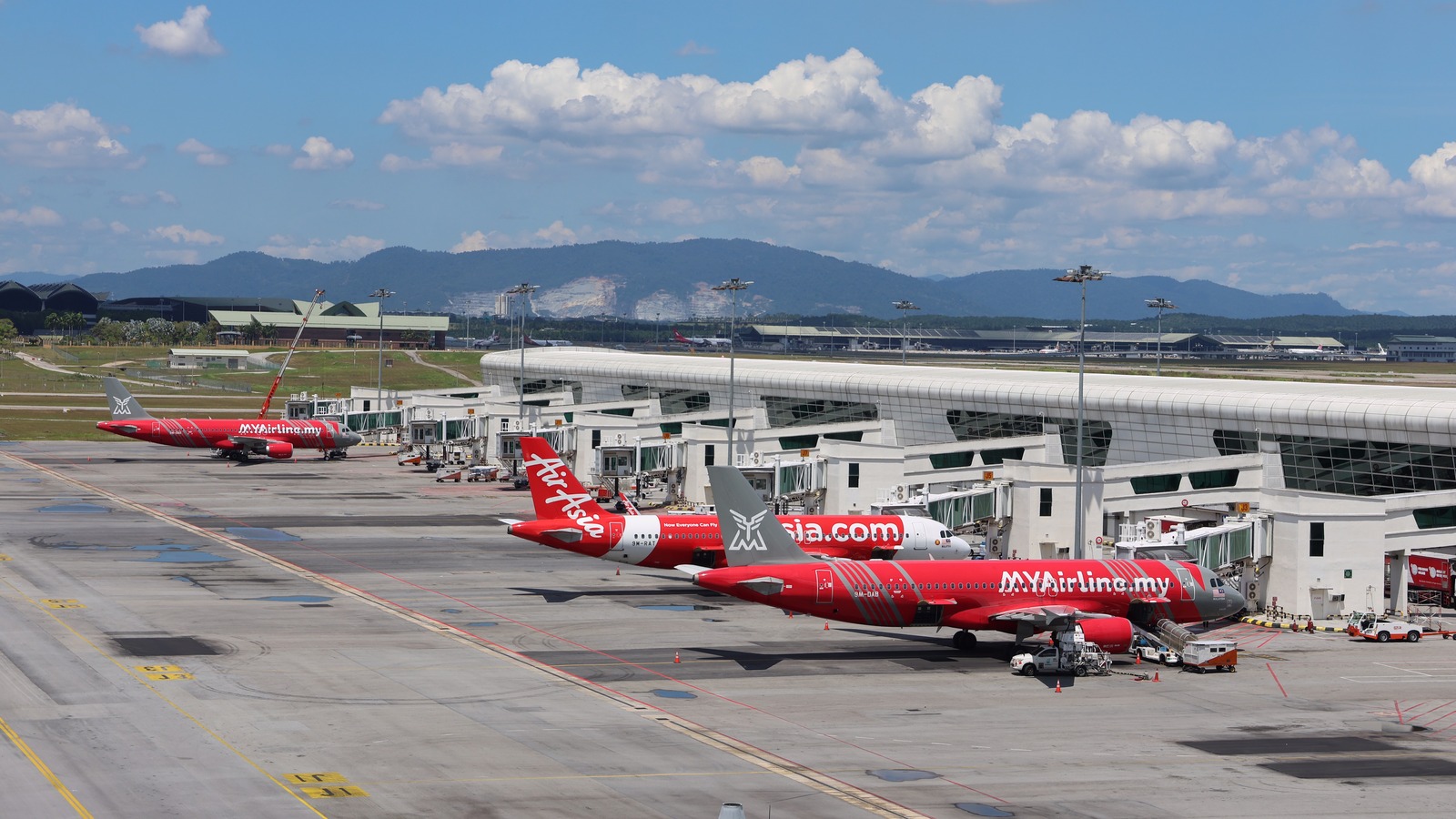 AirAsia aircraft parked at gates along the KLIA Terminal 2 apron in Sepang, Malaysia, under a bright sky