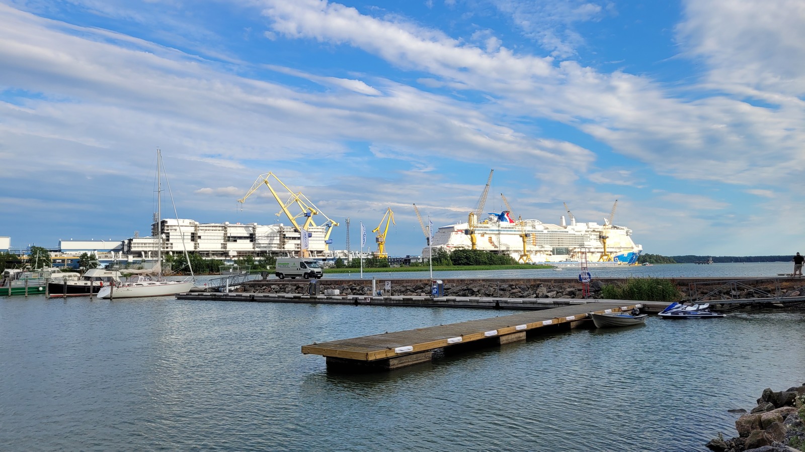Cruise ships under construction at the Meyer Turku shipyard in Turku, Finland, with cranes along the waterfront.