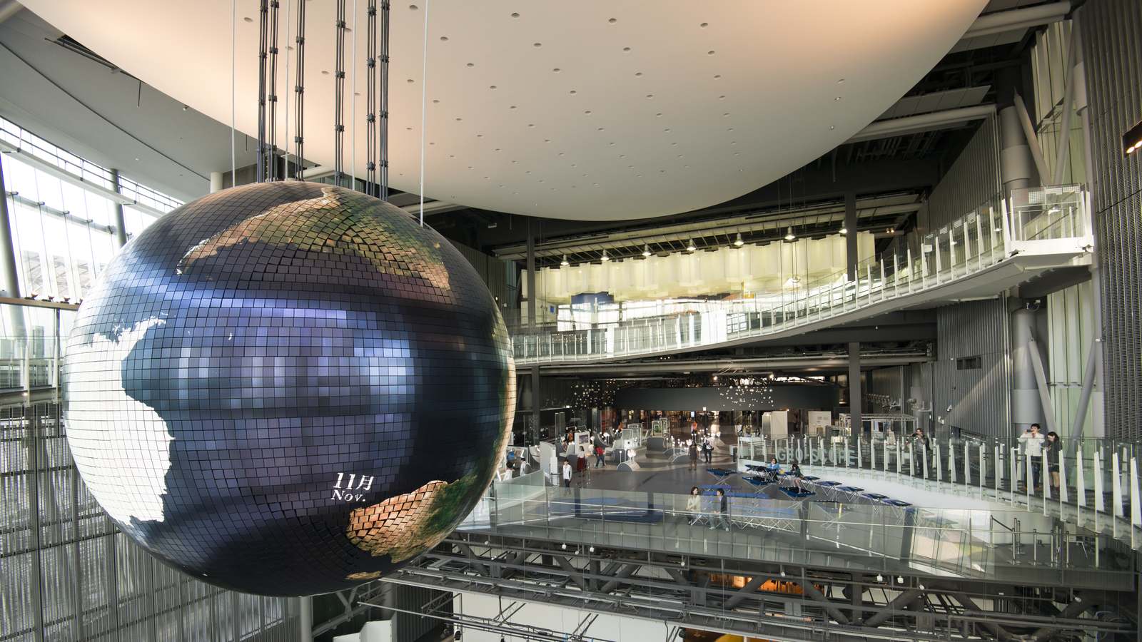 The Geo-Cosmos globe display hangs in Miraikan's atrium above walkways and exhibition floors inside the Tokyo science museum.