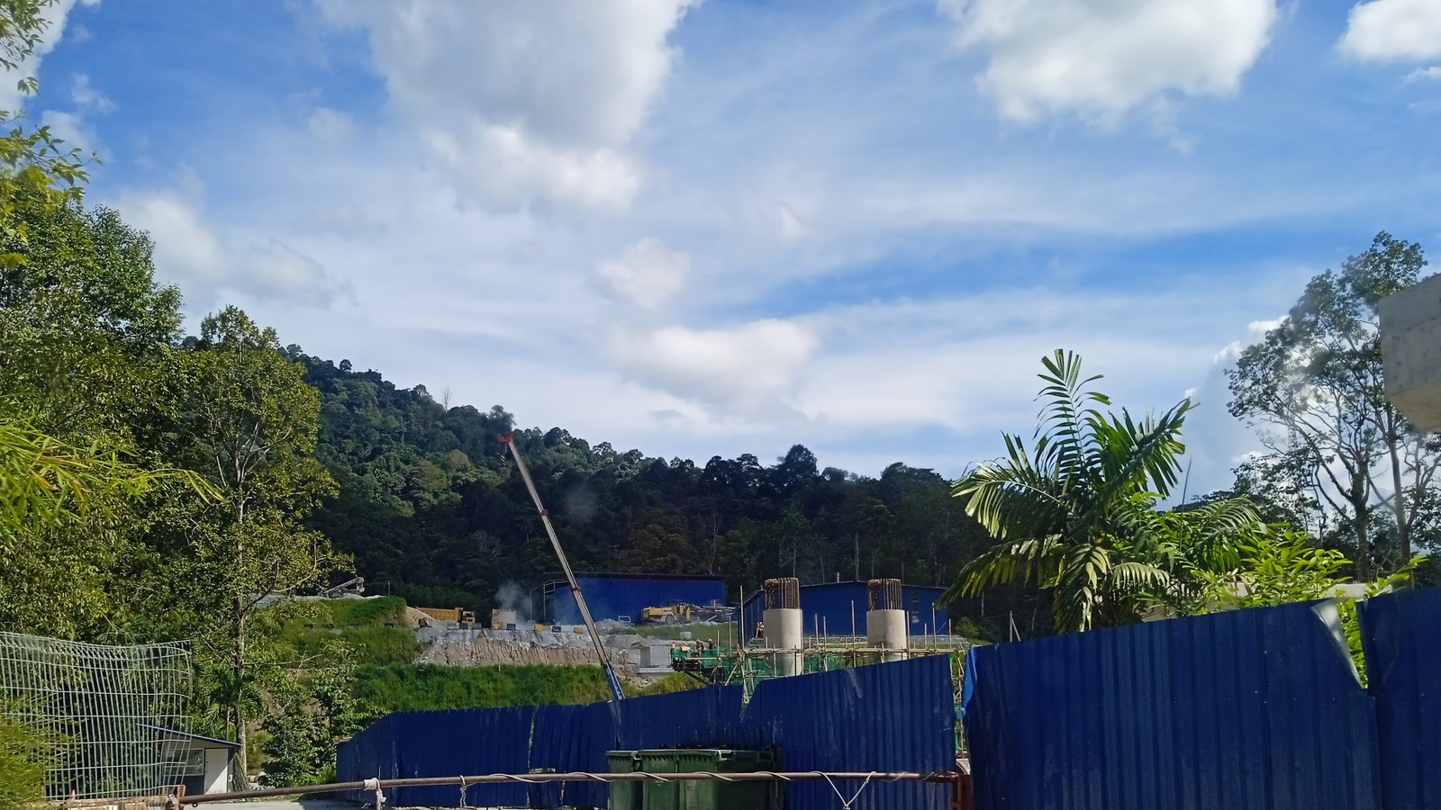 Daytime view of East Coast Rail Link construction earthworks and site buildings at Sungai Tua, Gombak, under a bright sky.