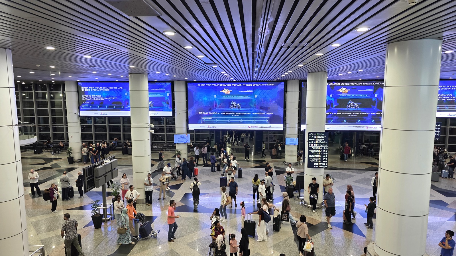 Travelers with luggage in the arrival hall of Kuala Lumpur International Airport Terminal 1