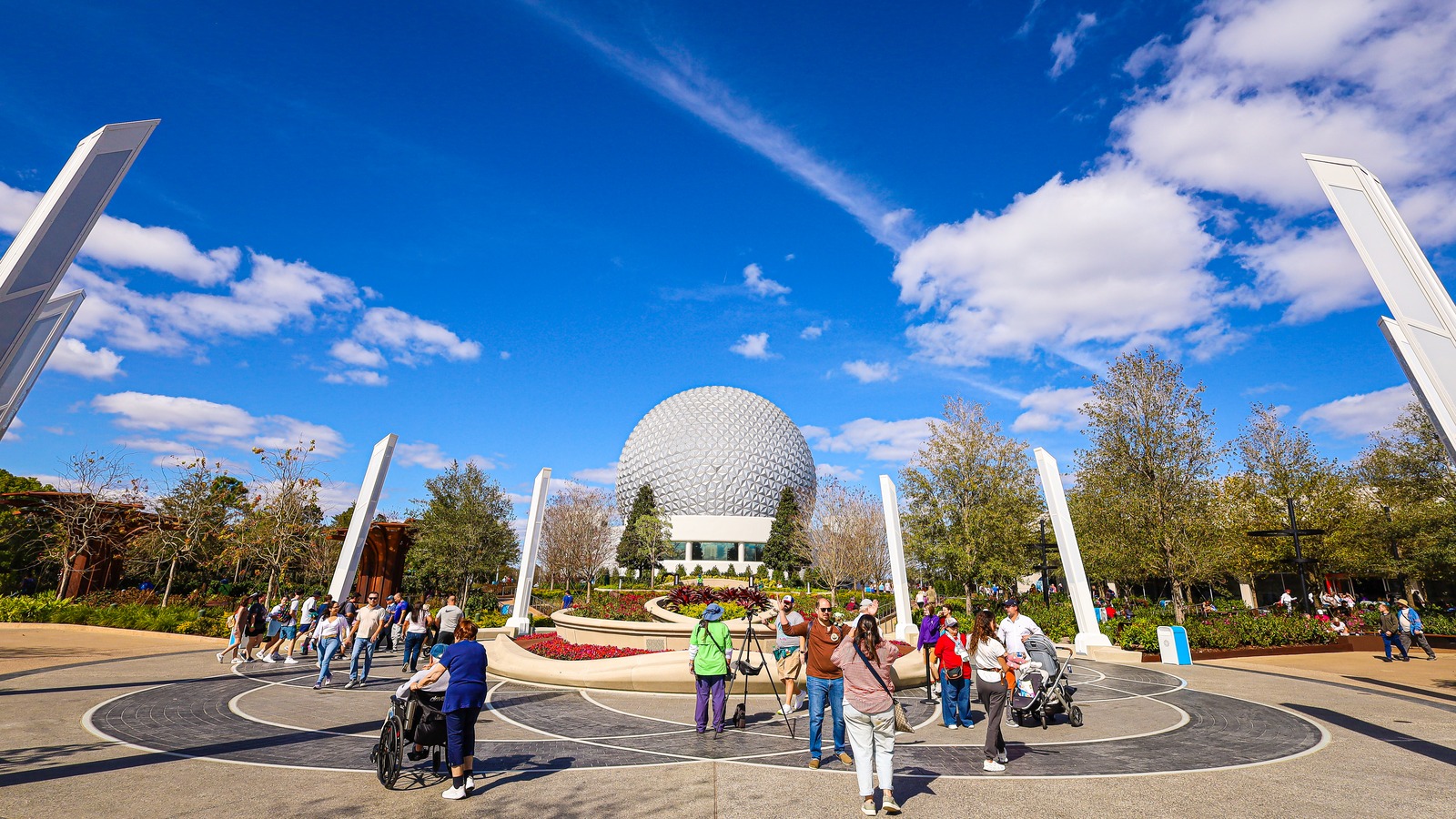 World Celebration gardens at EPCOT with Spaceship Earth in the background under a blue sky