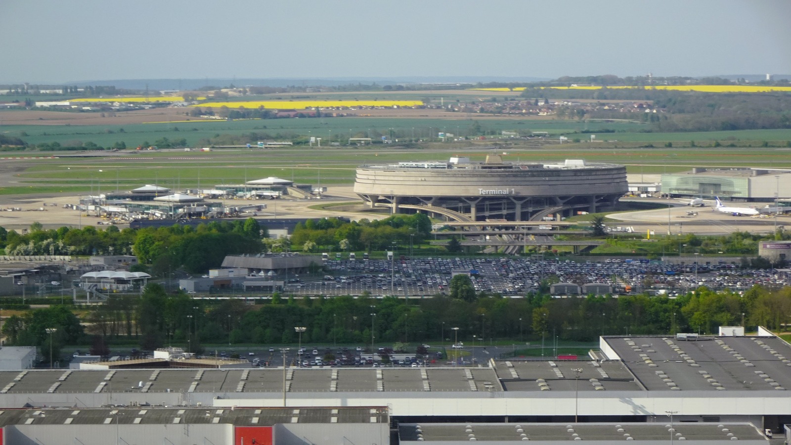 Aerial view of Paris Charles de Gaulle Airport Terminal 1 with runways and parked aircraft on a clear day