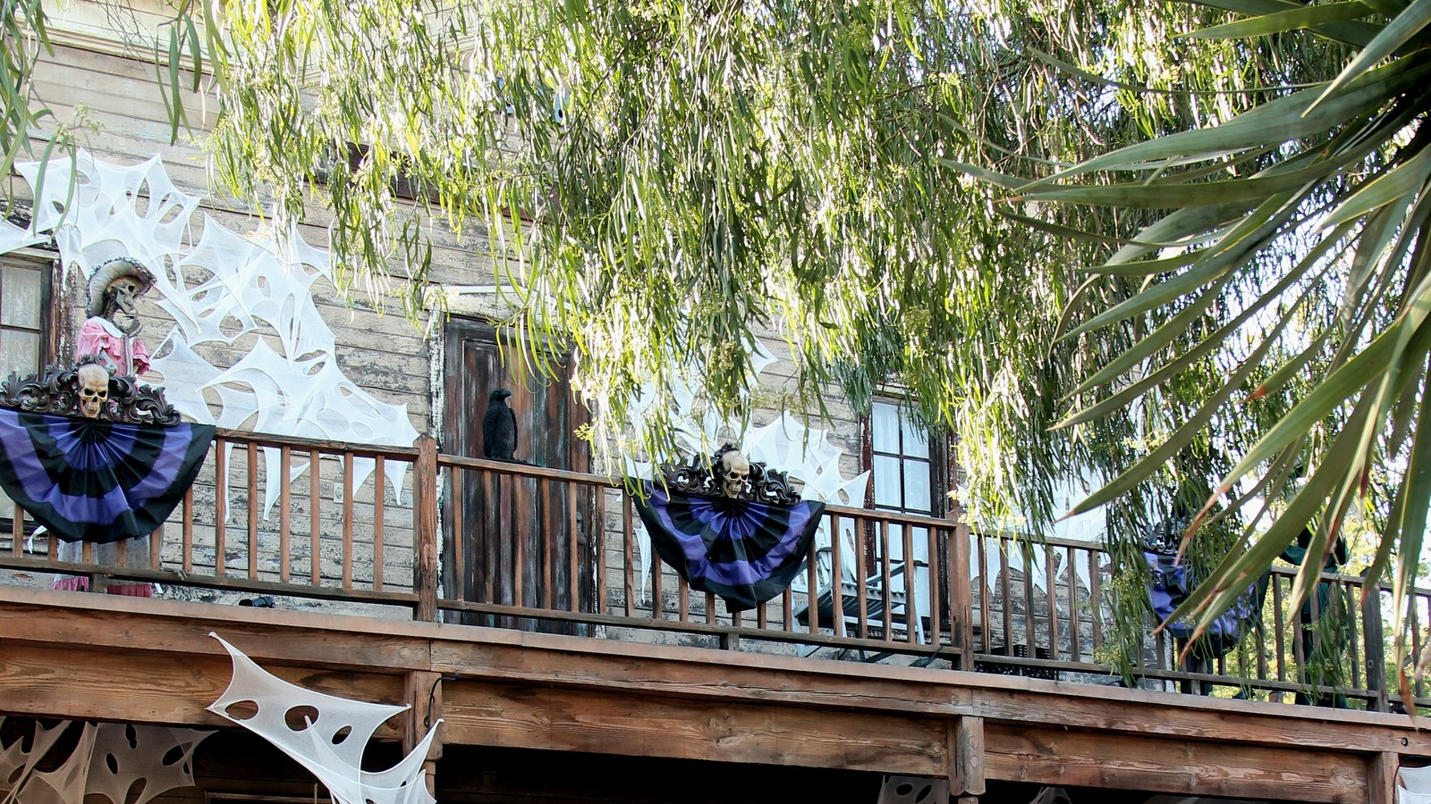 Halloween spiderwebs, skull bunting, and a costumed figure on a Ghost Town balcony at Knott's Berry Farm in Buena Park