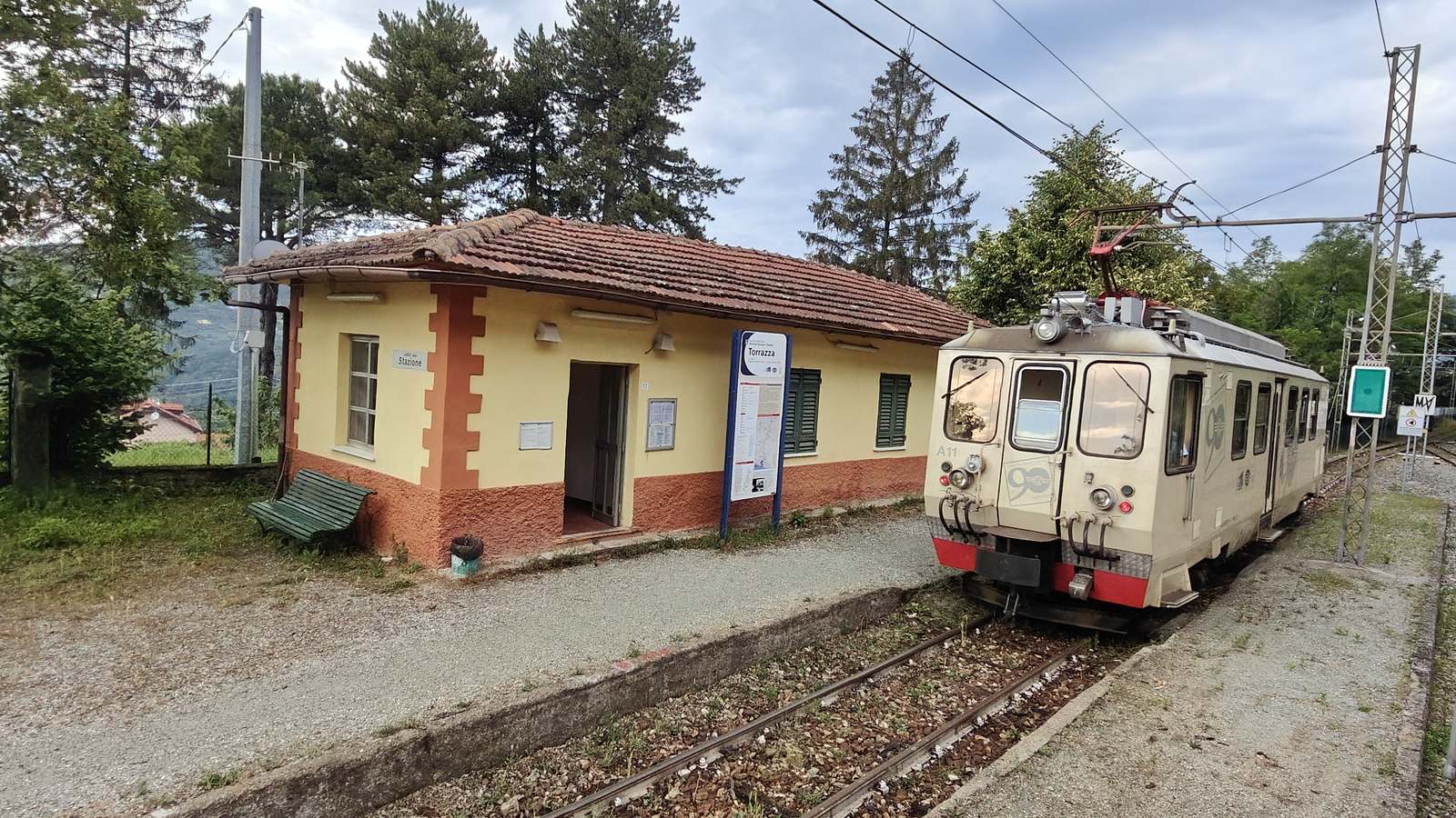 Cream Ferrovia Genova-Casella railcar standing at Torrazza station beside the yellow station building