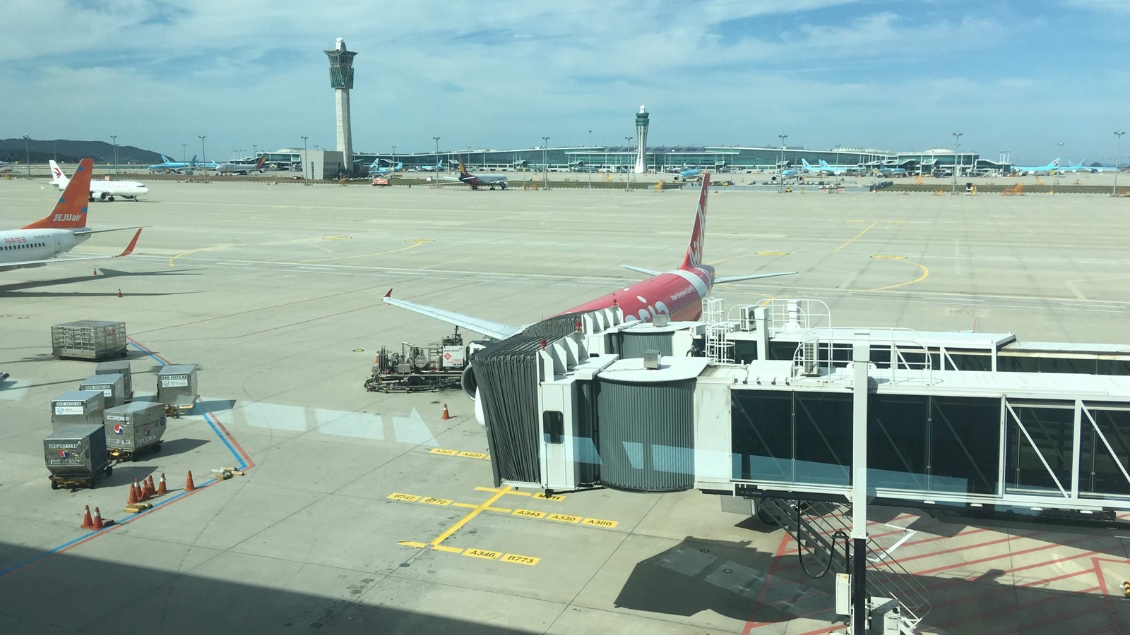 Incheon International Airport apron with the control tower, Terminal 2, and Korean Air and Jeju Air aircraft at the gates