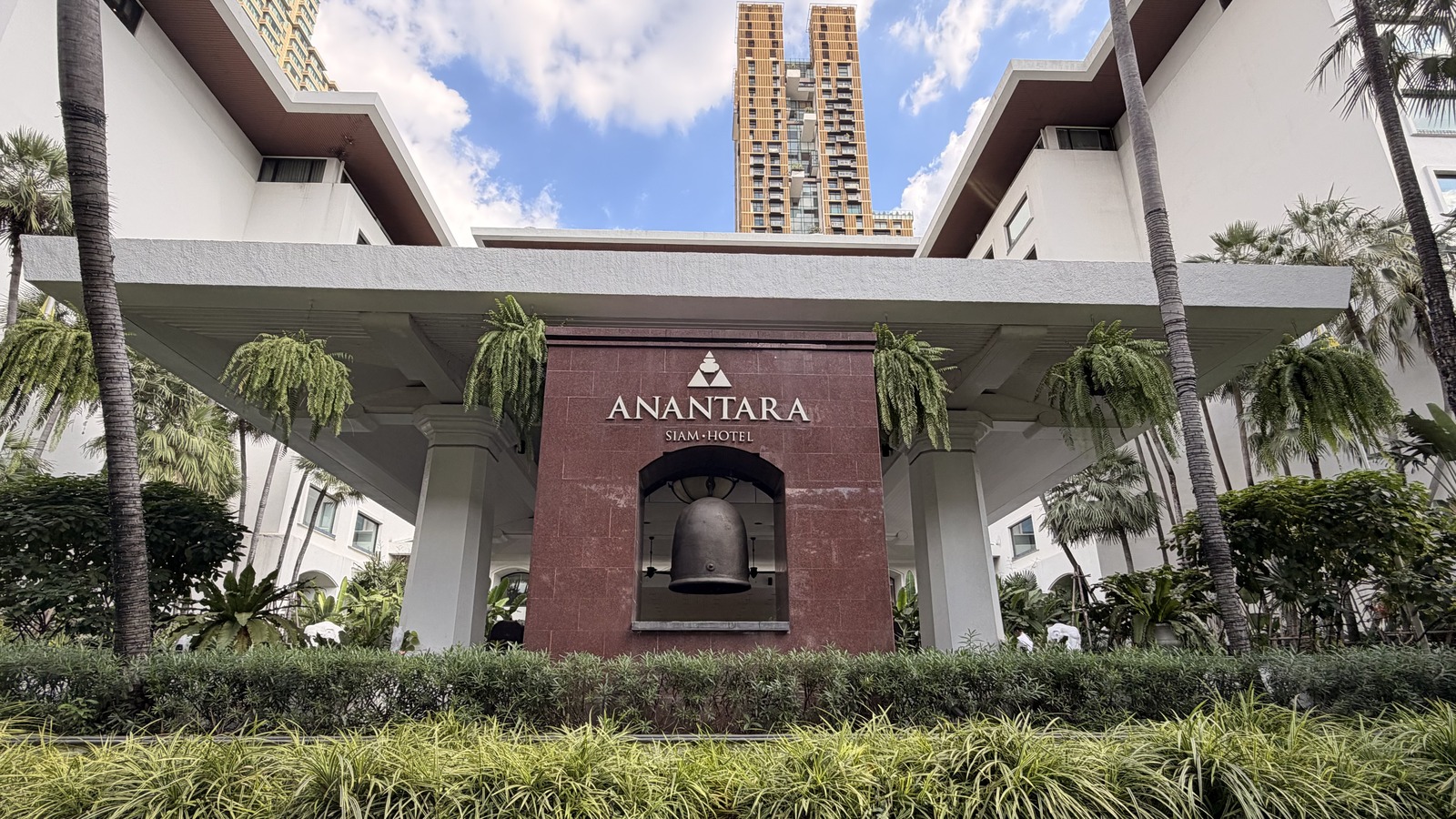 Entrance porte-cochere at Anantara Siam Bangkok Hotel with the hotel sign and bell on Ratchadamri Road