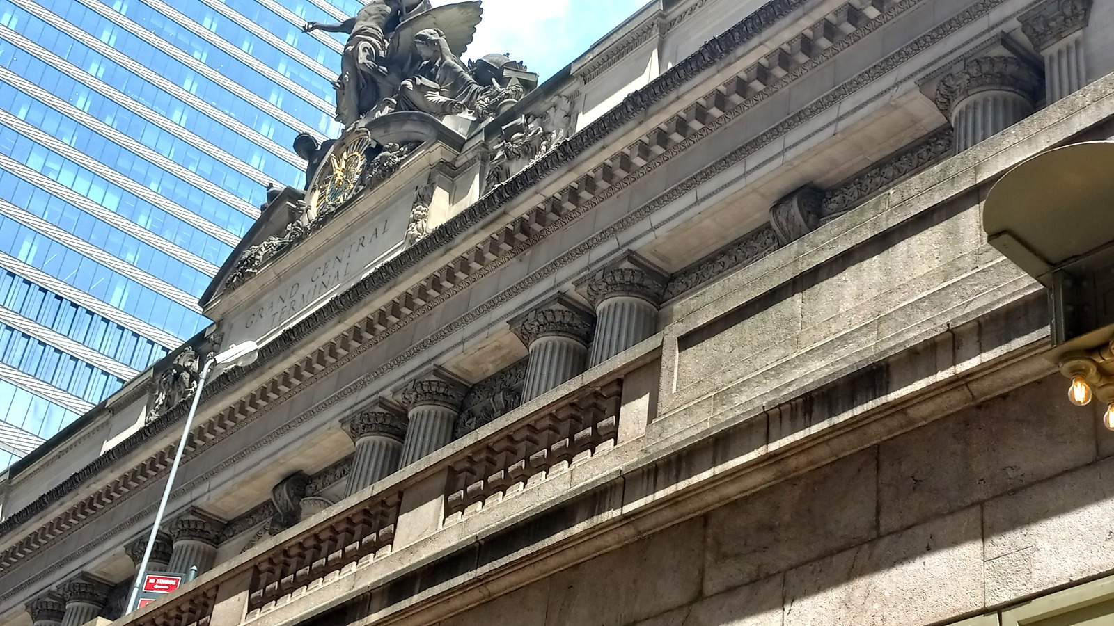 Daytime exterior of Grand Central Terminal facade with stone columns and rooftop sculpture