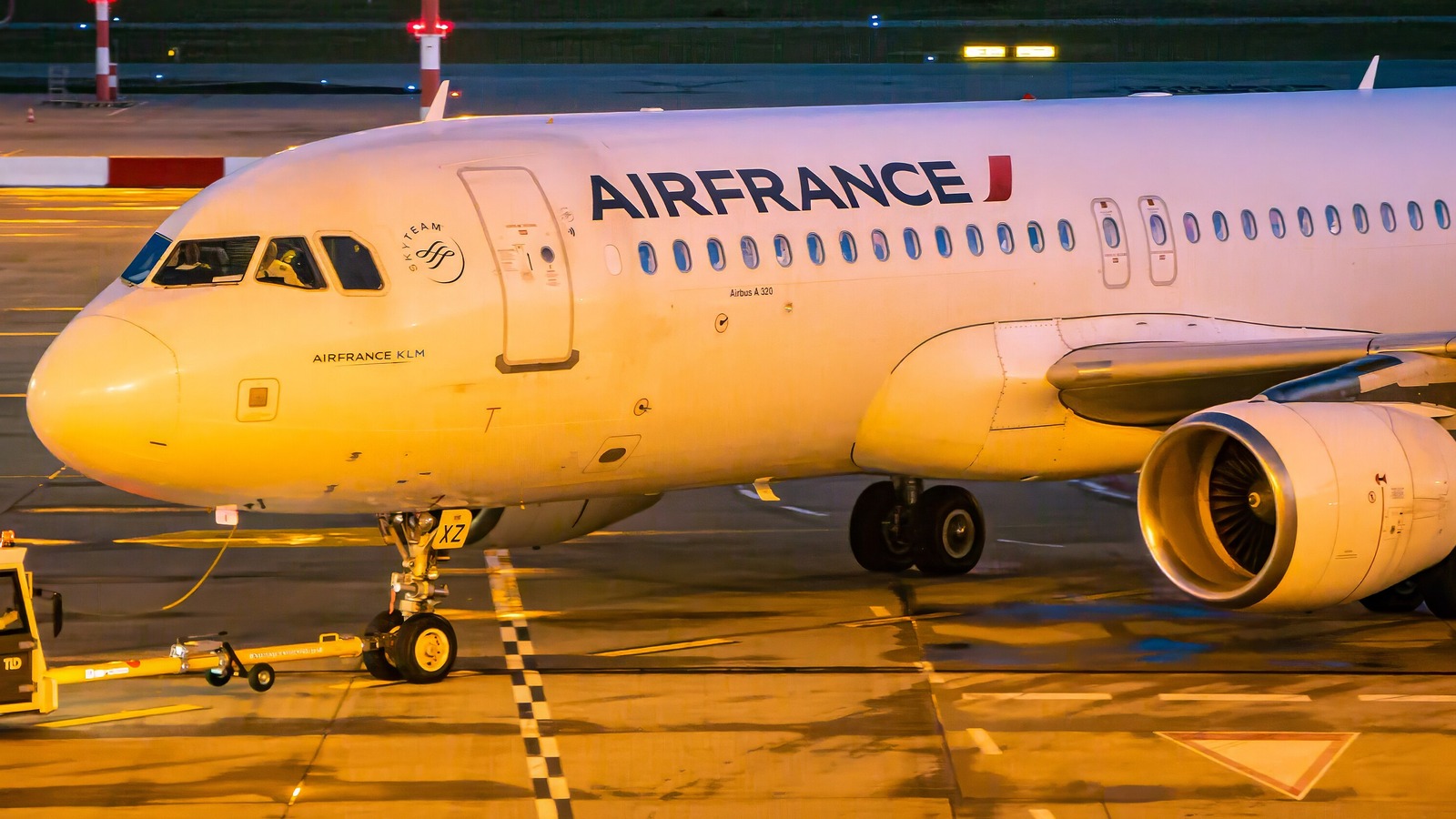 An Air France Airbus A320 with the AIRFRANCE wordmark along the forward fuselage on an airport apron at dusk.