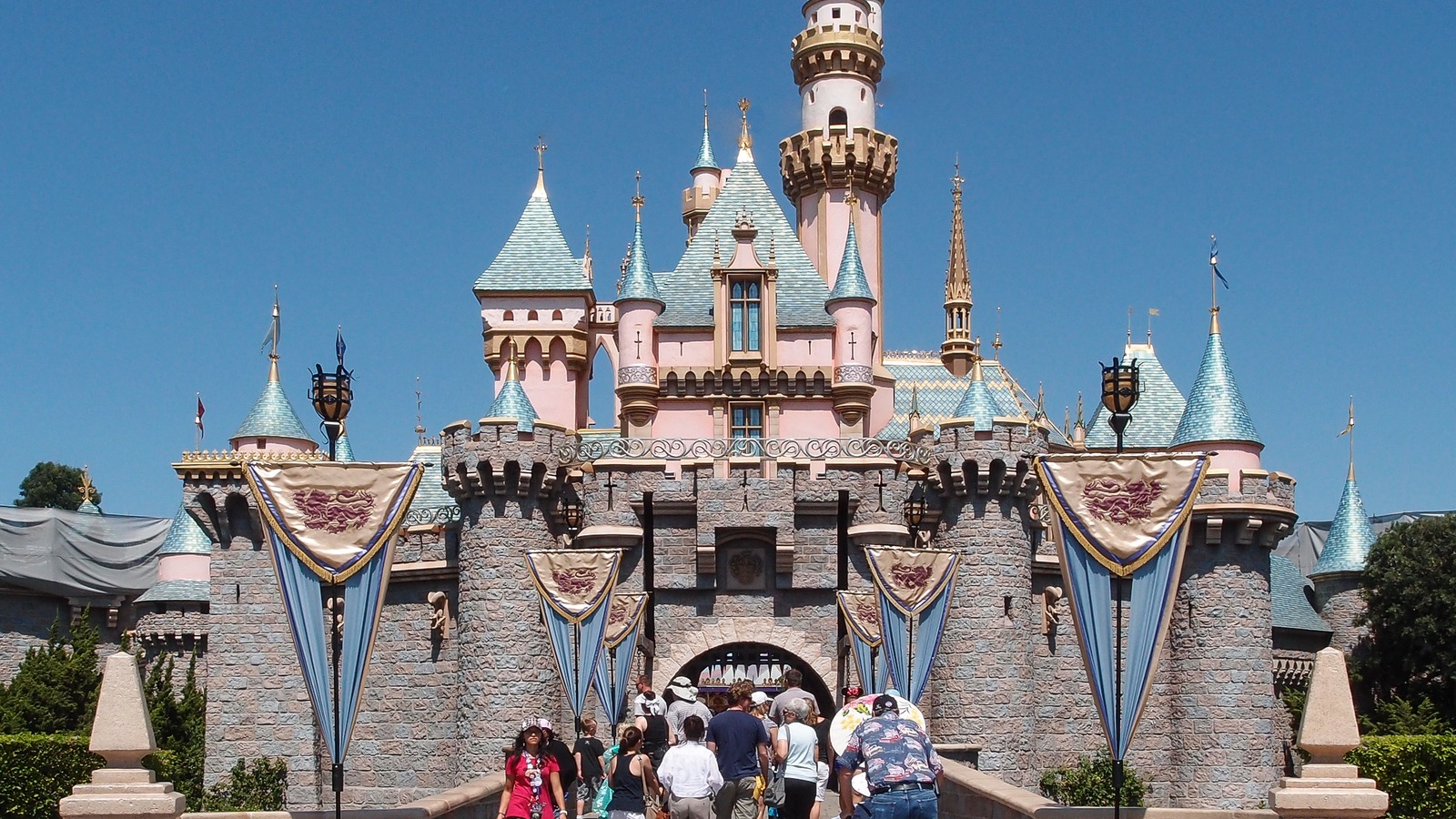 Sleeping Beauty Castle at Disneyland in Anaheim with guests crossing the castle drawbridge under a clear sky