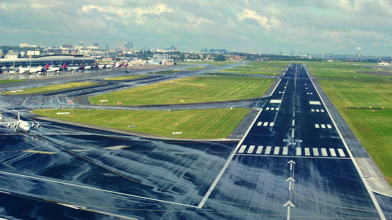 Daytime view over runway 25R at Brussels Airport with parked aircraft and terminal buildings
