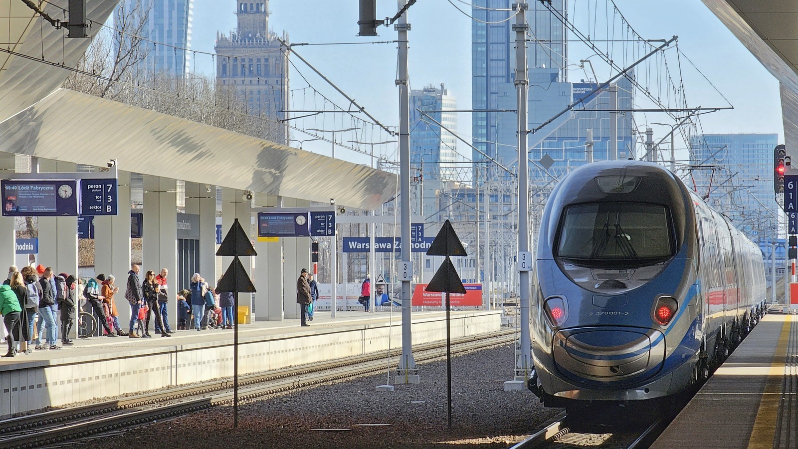 A PKP Intercity Pendolino train arrives at Warszawa Zachodnia station in Warsaw as passengers wait on the platform.