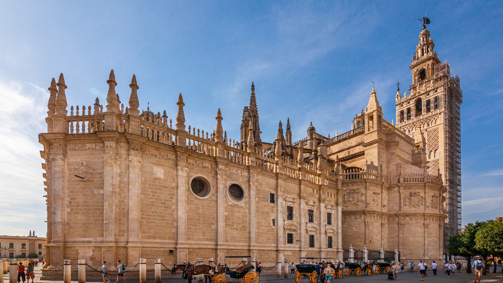 West facade of Seville Cathedral in daylight with the Giralda rising behind the Gothic portals