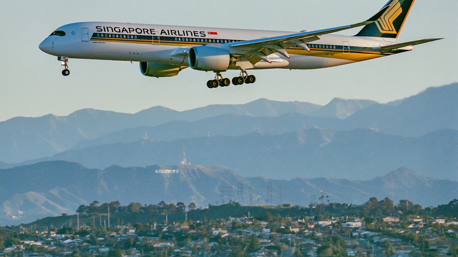 A Singapore Airlines Airbus A350-900ULR on final approach to Los Angeles International Airport, with the San Gabriel Mountains and the Hollywood sign behind.