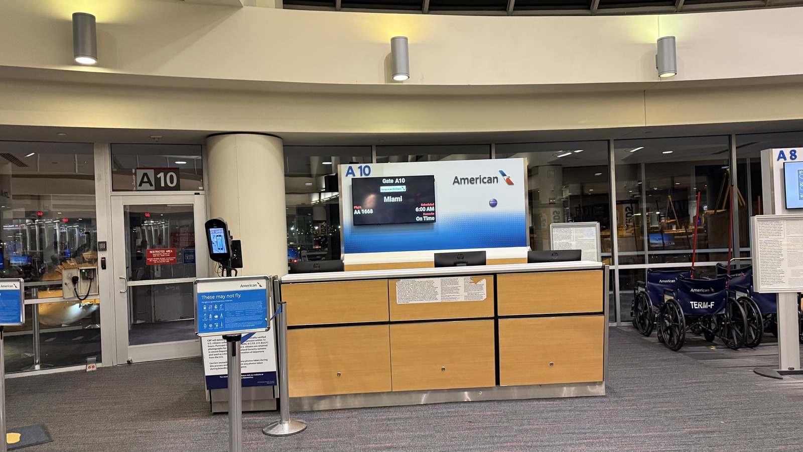 The empty gate A10 podium at Philadelphia International Airport, with an American Airlines sign and a departure screen showing an early morning flight to Miami, under a low ceiling with no windows to the outside.