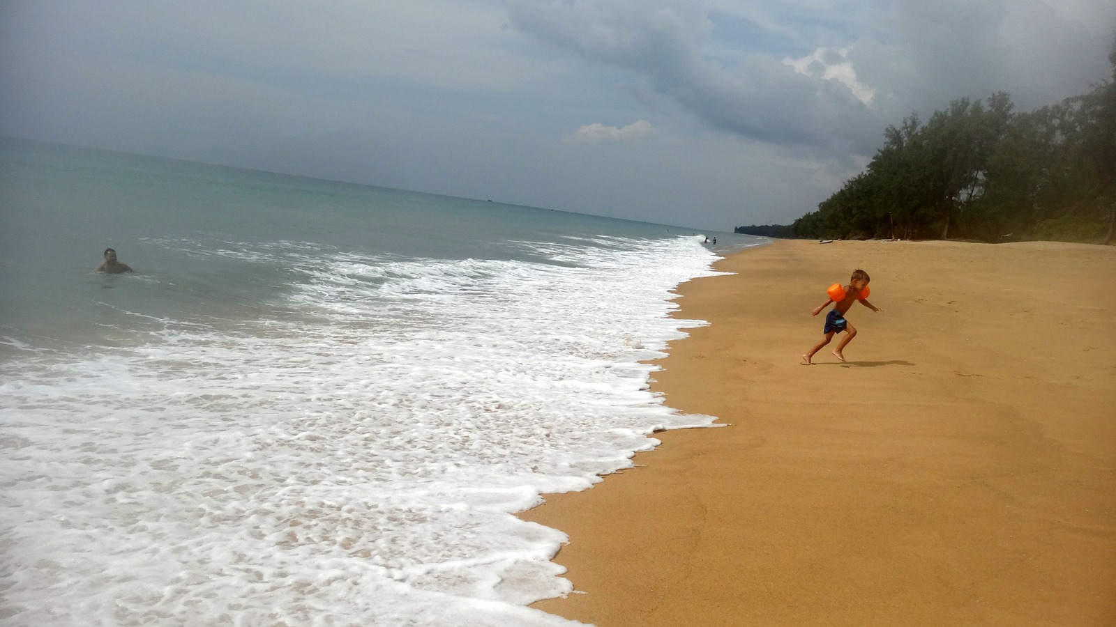 Sandy shoreline and calm sea at Mai Khao Beach, Phuket, in daylight
