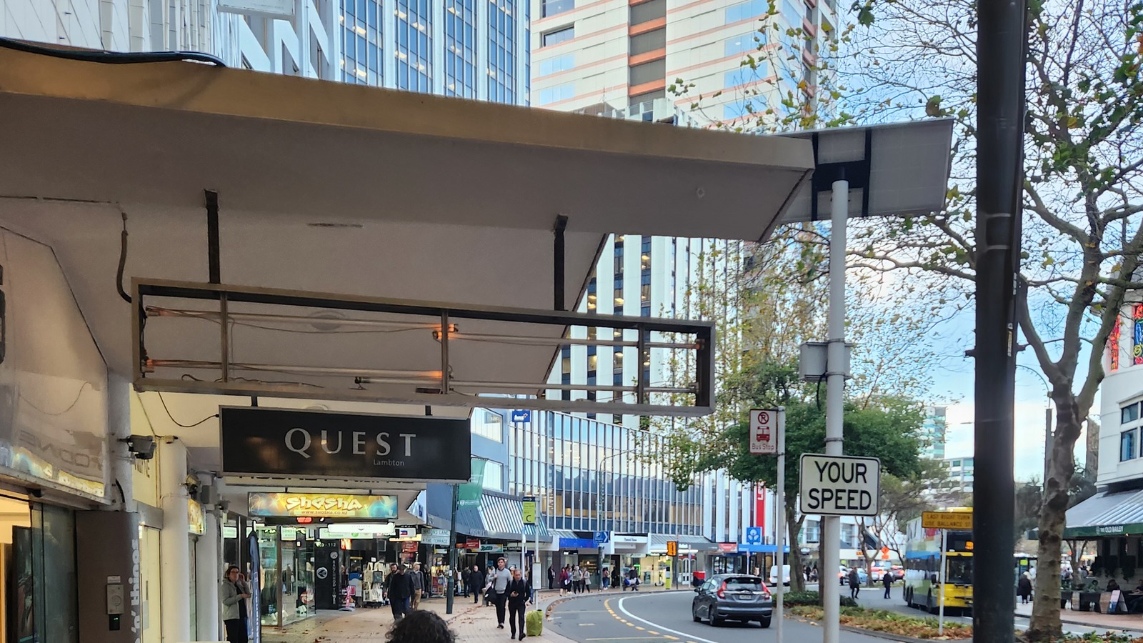 Daytime street view of Lambton Quay in Wellington, with shops, pedestrians and buses under office towers