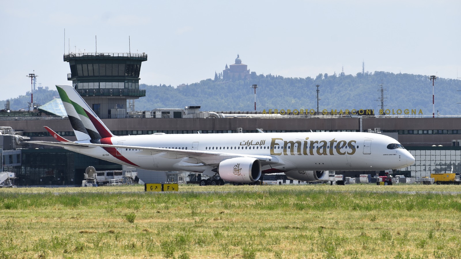 Emirates Airbus A350-900 taxiing at Bologna Airport, with the Guglielmo Marconi terminal behind the aircraft