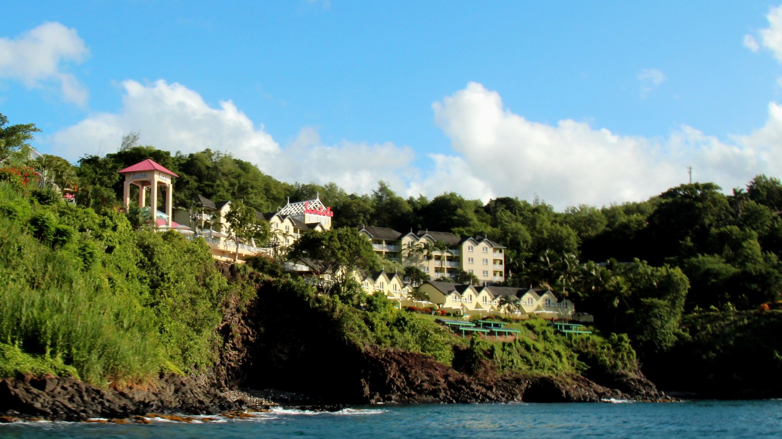 Sandals La Toc resort buildings on a green hillside above the sea in Saint Lucia, photographed from the water in 2015