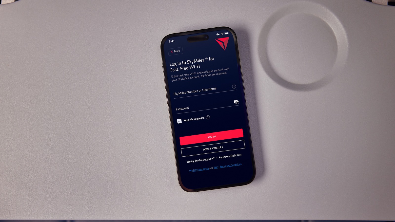 Phone showing the Delta Sync Wi-Fi login screen on an aircraft tray table