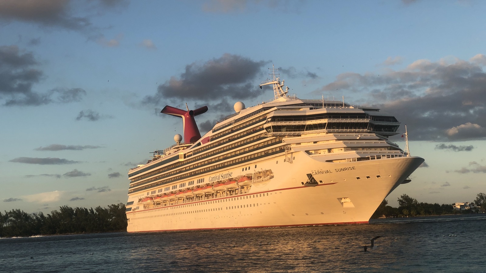 Carnival Sunrise cruise ship in Nassau harbor with bow lettering visible at sunset