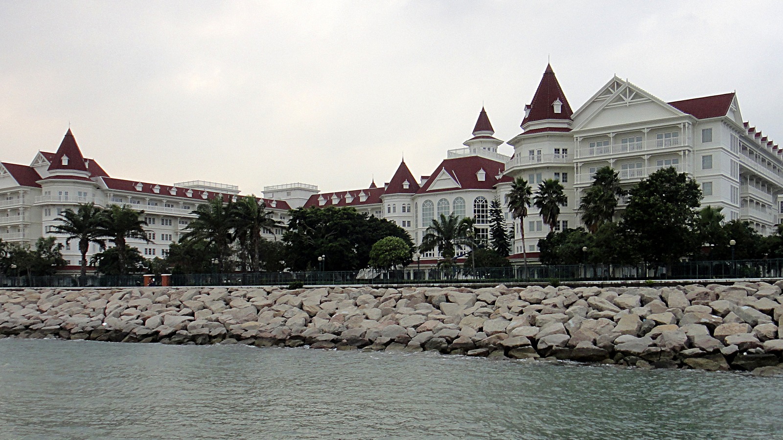 Hong Kong Disneyland Hotel Victorian white facade with red roofs seen across the water