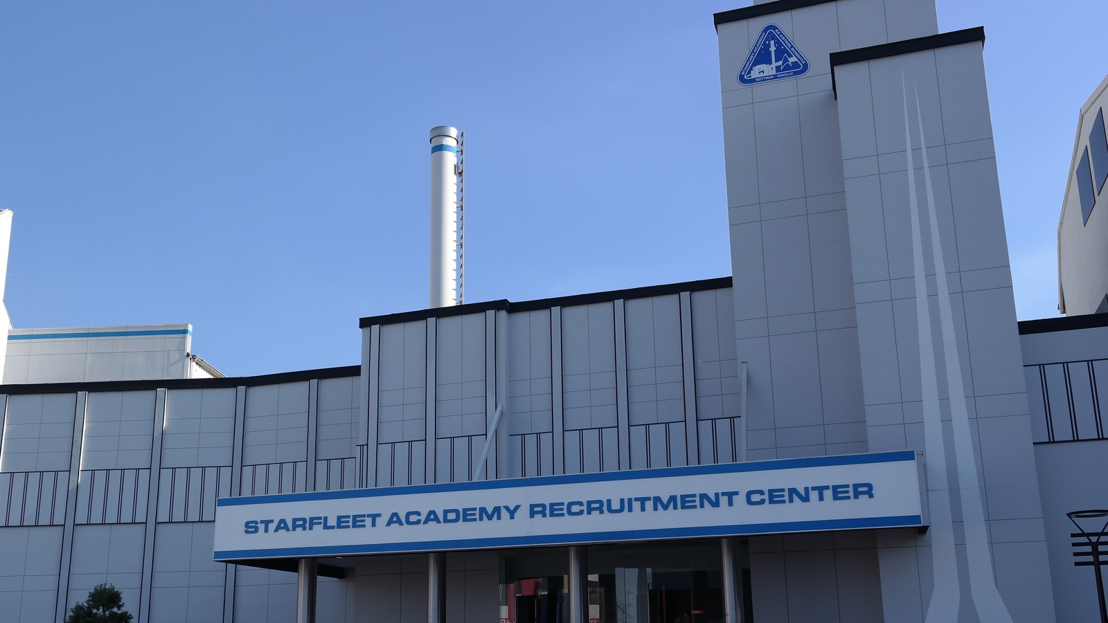 The Star Trek Operation Enterprise building at Movie Park Germany in Bottrop, with guests sitting on the entrance steps under a clear sky.