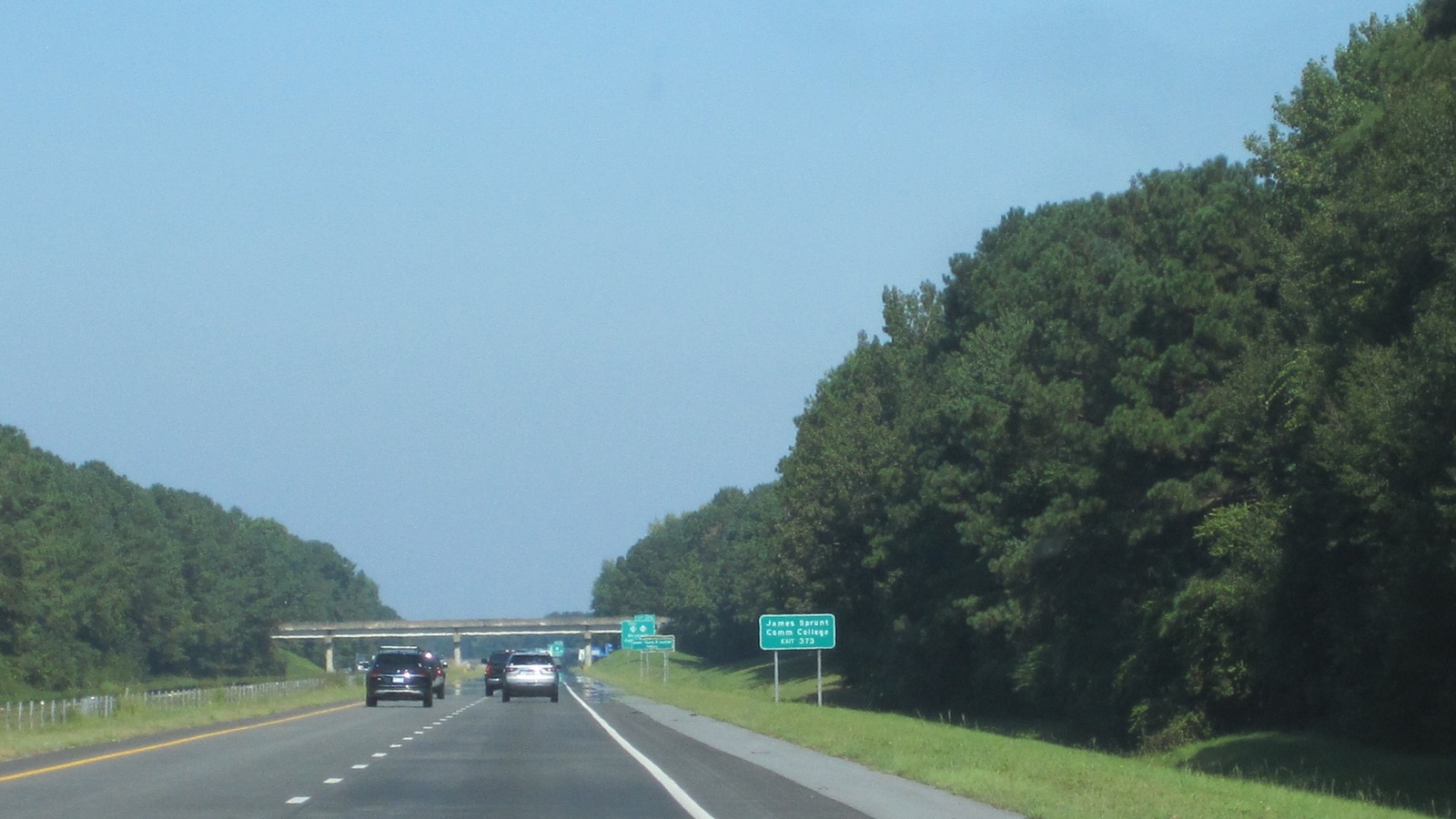 Daytime view of Interstate 40 in North Carolina with green exit signs and an overpass