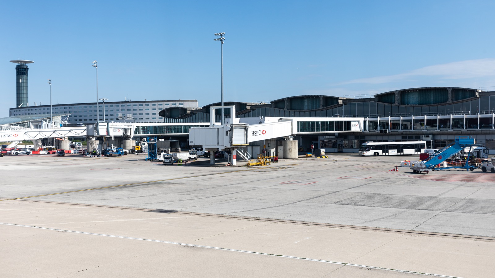Jet bridges at Terminal 2 of Paris Charles de Gaulle Airport on a clear day, with the control tower at left.