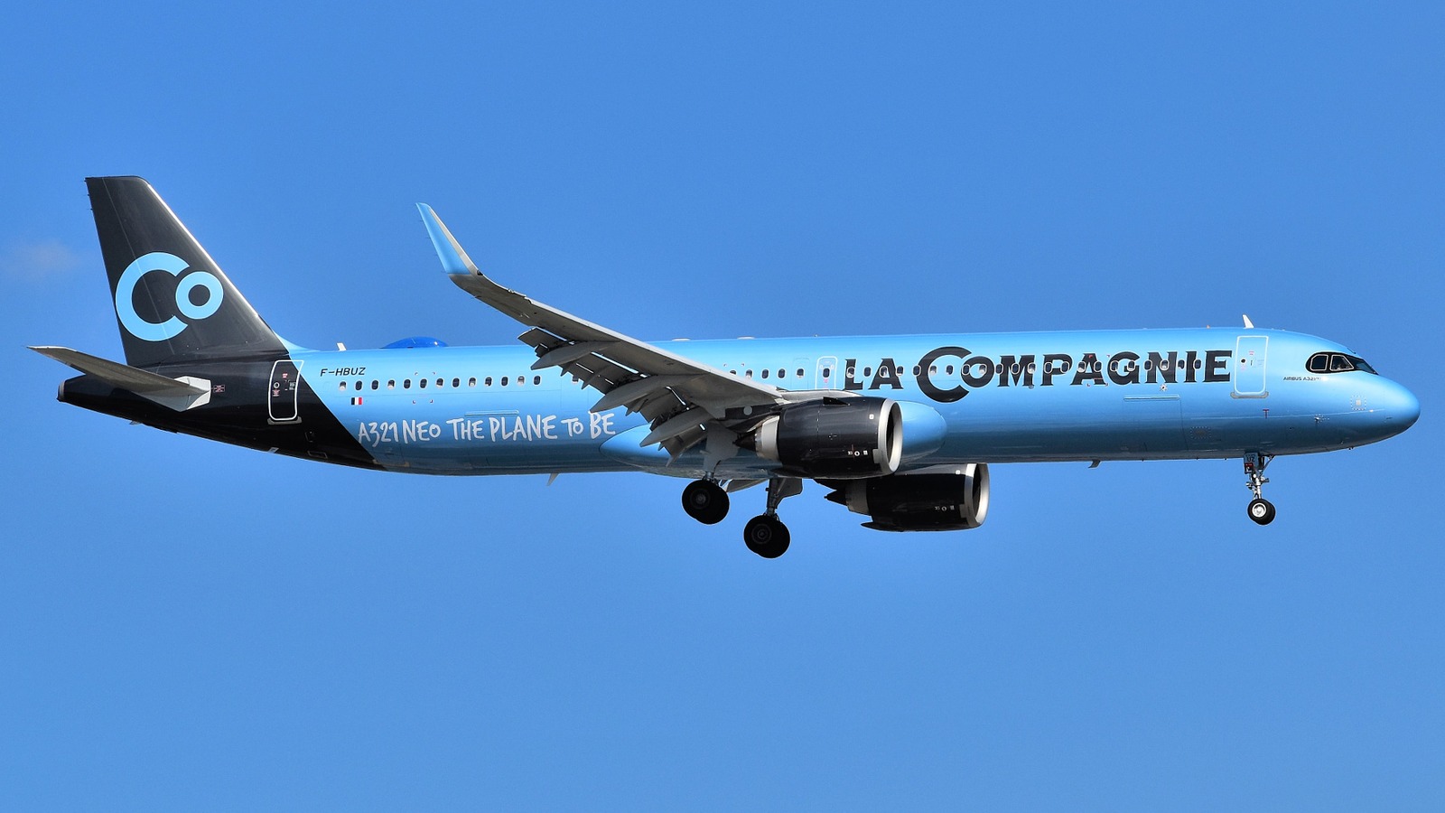 La Compagnie Airbus A321neo F-HBUZ in light blue livery approaching Newark Liberty International Airport against a clear blue sky