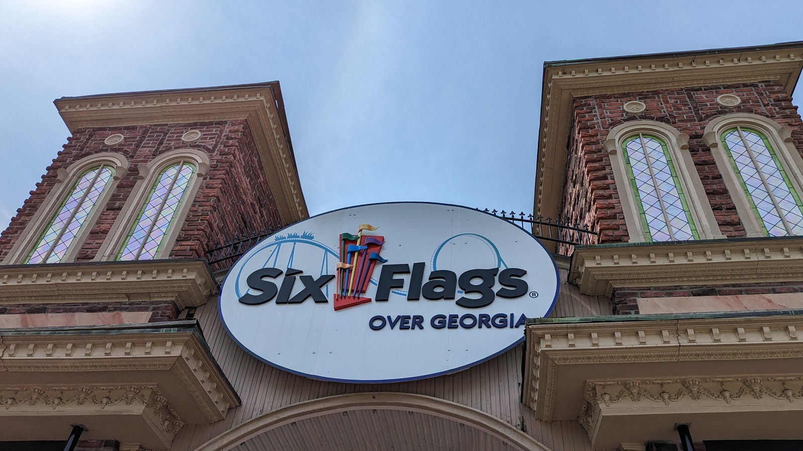 The main entrance gate at Six Flags Over Georgia, with the park sign mounted between two brick towers under a clear sky
