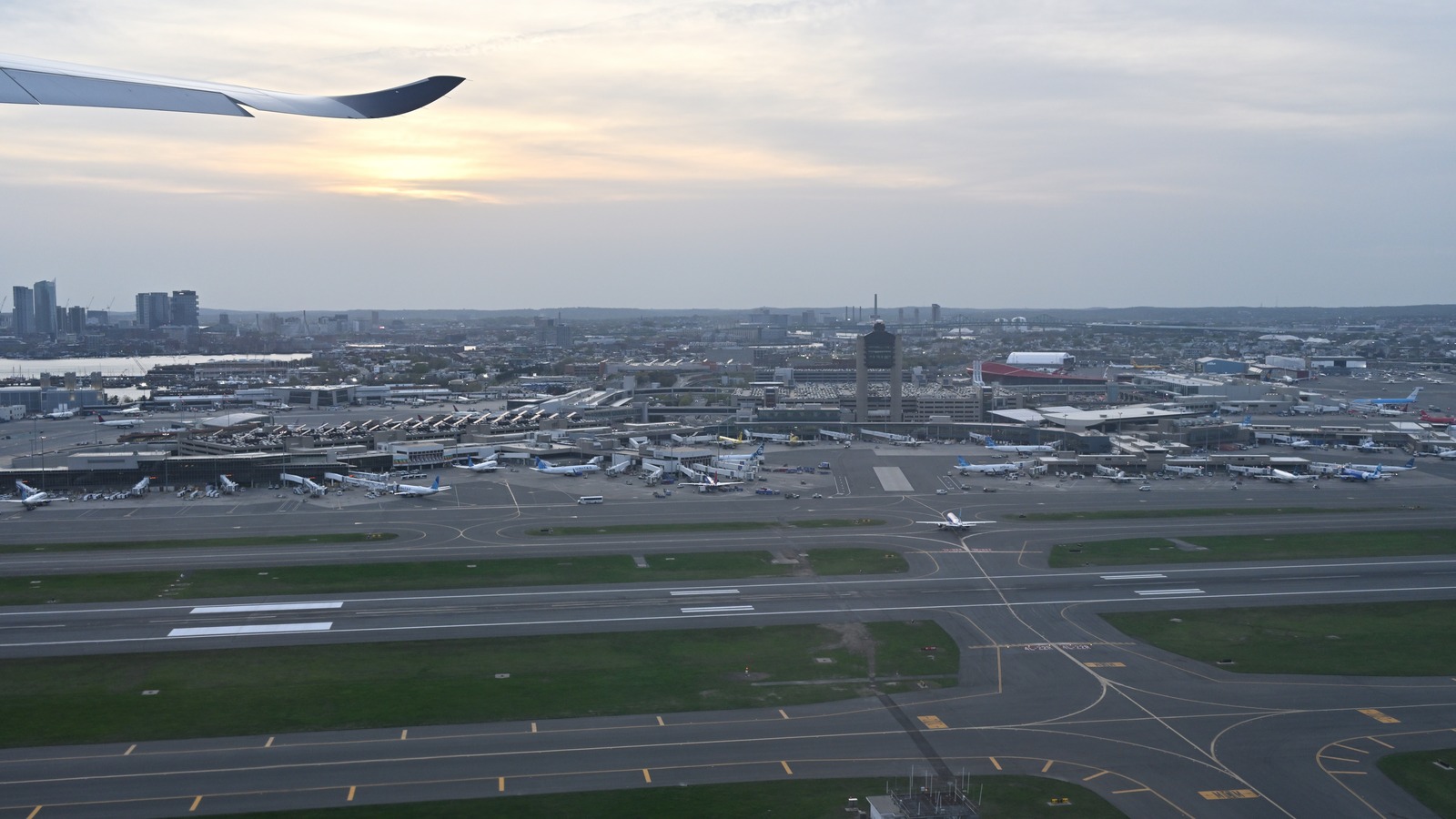 Aerial view of Boston Logan International Airport terminals, tower, and runways from a departing aircraft