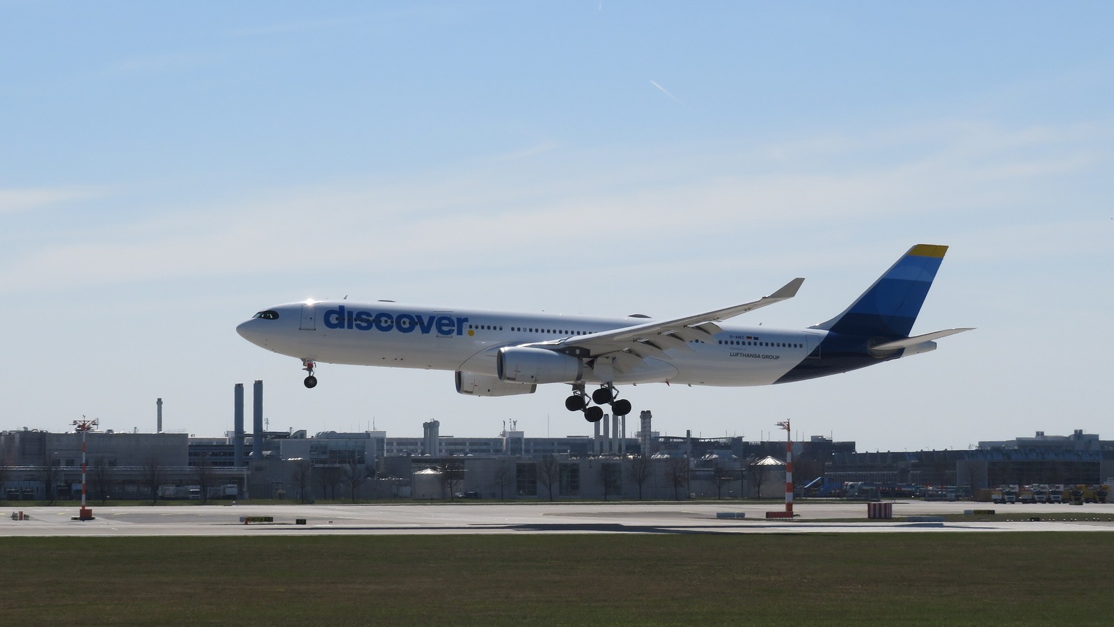 A Discover Airlines Airbus A330-300 with blue discover titles and Lufthansa Group markings landing at Munich Airport.