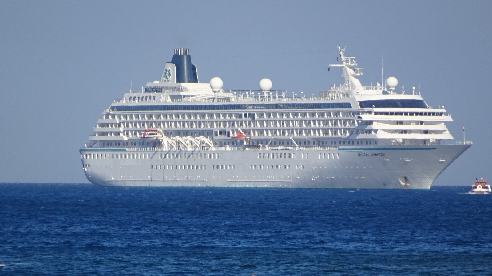 The cruise ship Crystal Symphony at anchor in open water with a tender alongside, the ship that opened Manta's 2026-27 season