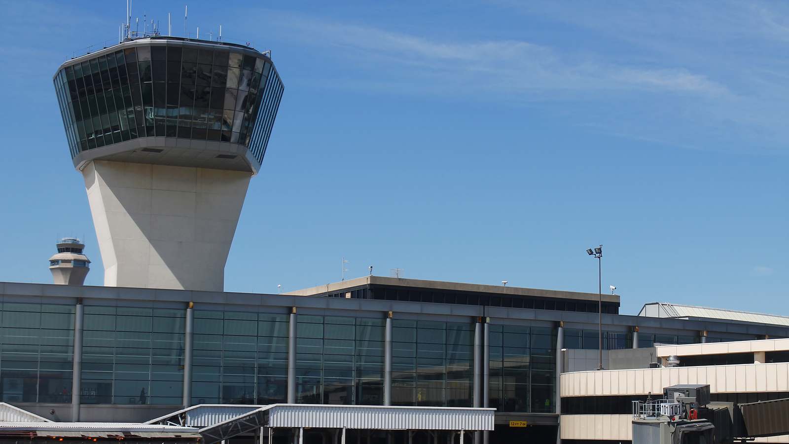 Air traffic control towers rising above a terminal at Newark Liberty International Airport under a clear blue sky.