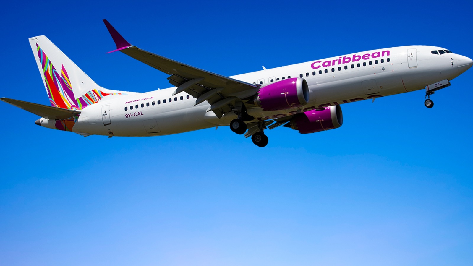 A Caribbean Airlines Boeing 737 in flight against a blue sky