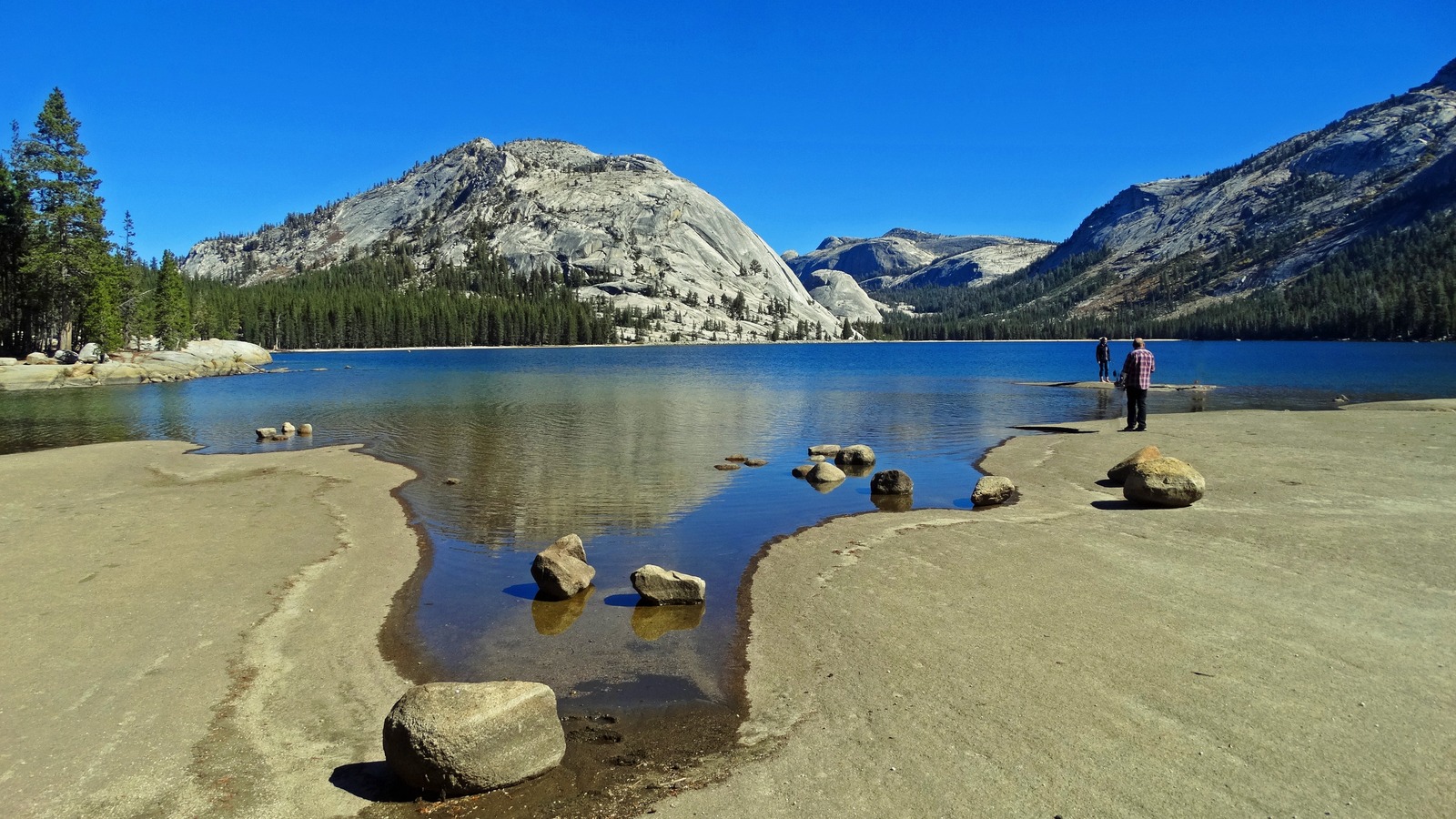Tenaya Lake beside Tioga Road in Yosemite National Park with granite domes and shoreline visitors