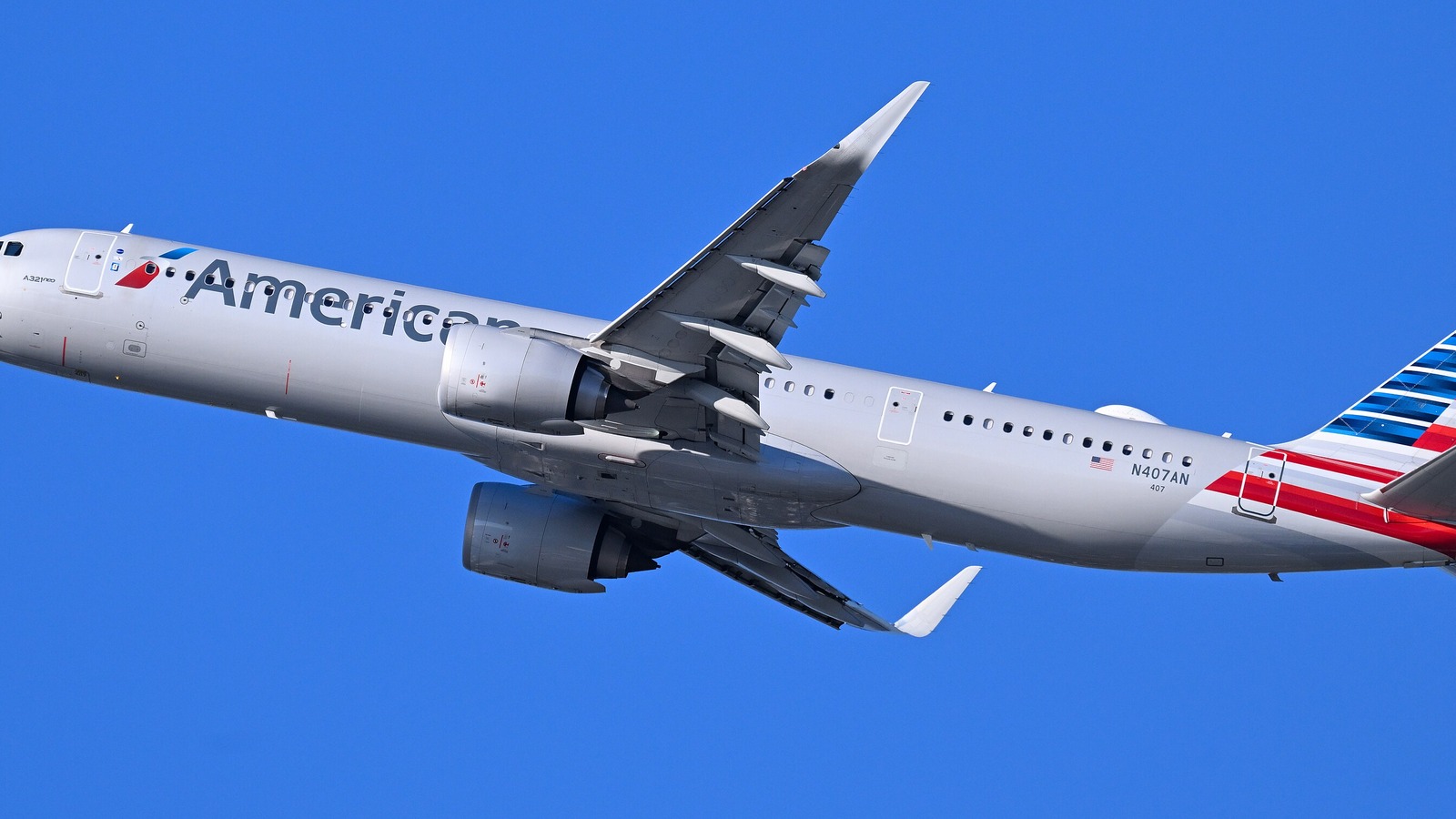 An American Airlines Airbus A321neo climbing after takeoff against a clear blue sky, with the American titles and tail livery visible.