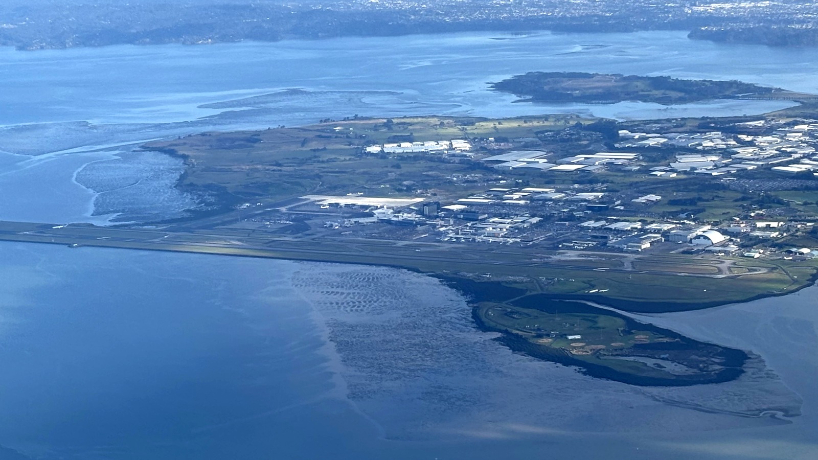 Aerial view of Auckland Airport runways and terminal area beside the harbor, photographed April 3, 2026