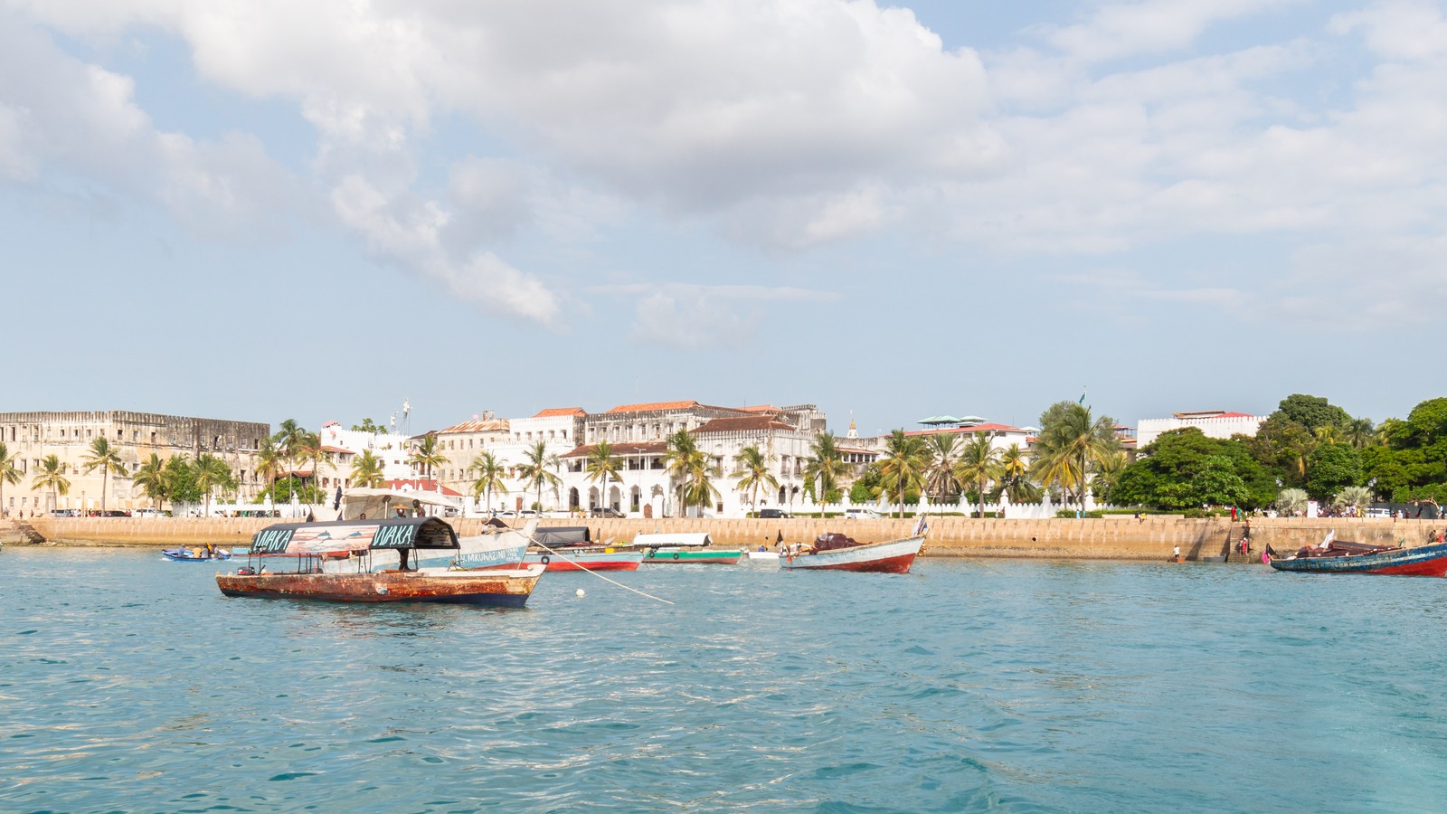 Stone Town harbour in Zanzibar with boats on turquoise water and white waterfront buildings