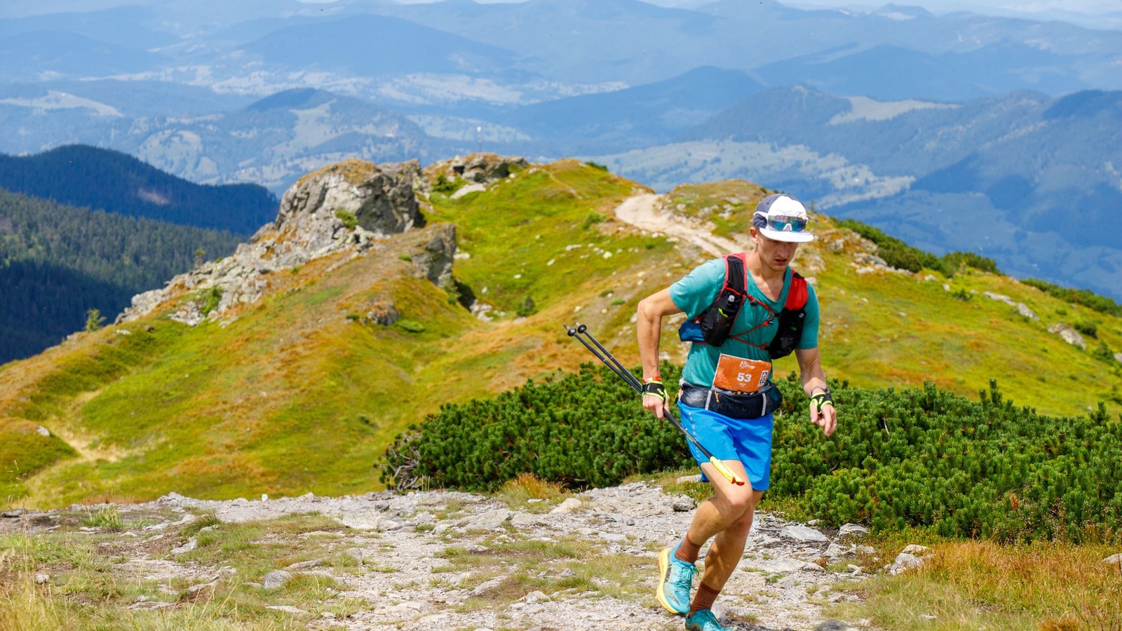 A trail runner wearing a hydration pack in mountain terrain.