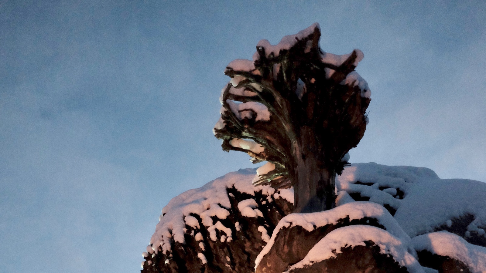 Snow-covered root-shaped staff and hand detail of the Hunderfossen Troll in December 2021